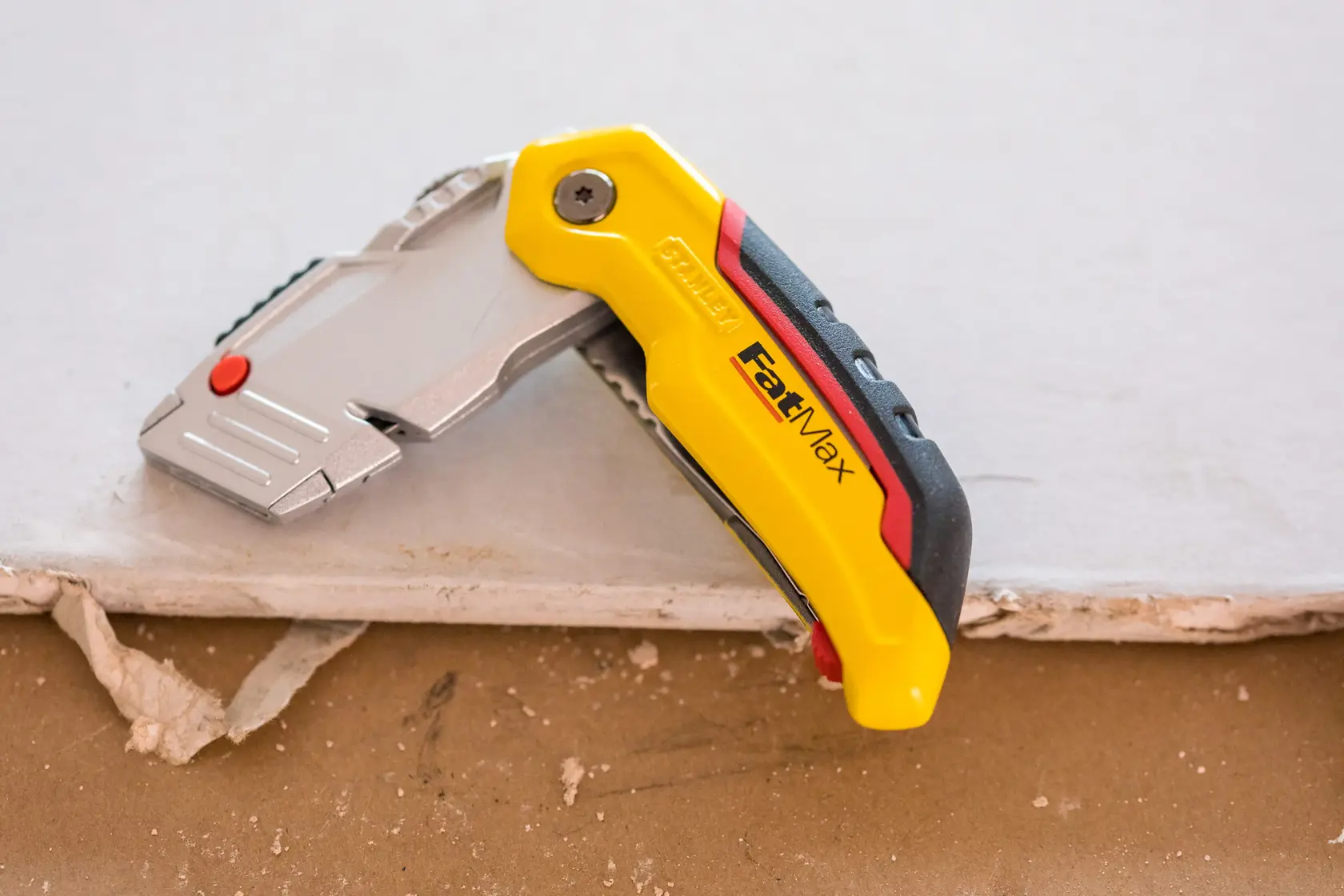 STANLEY 0-10-825 utility knife FatMax model on drywall, yellow and black ergonomic handle.