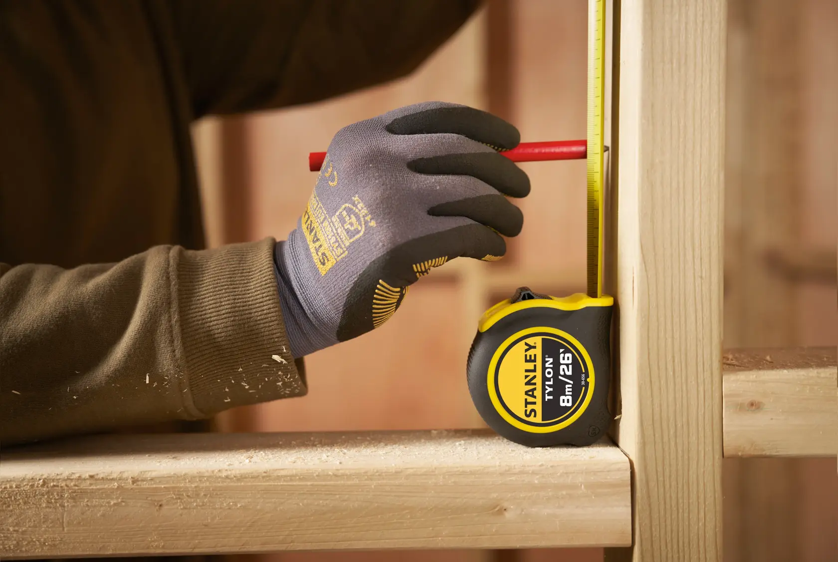 STANLEY 0-30-656 tape measure held in gloved hand, marking wood on construction site.