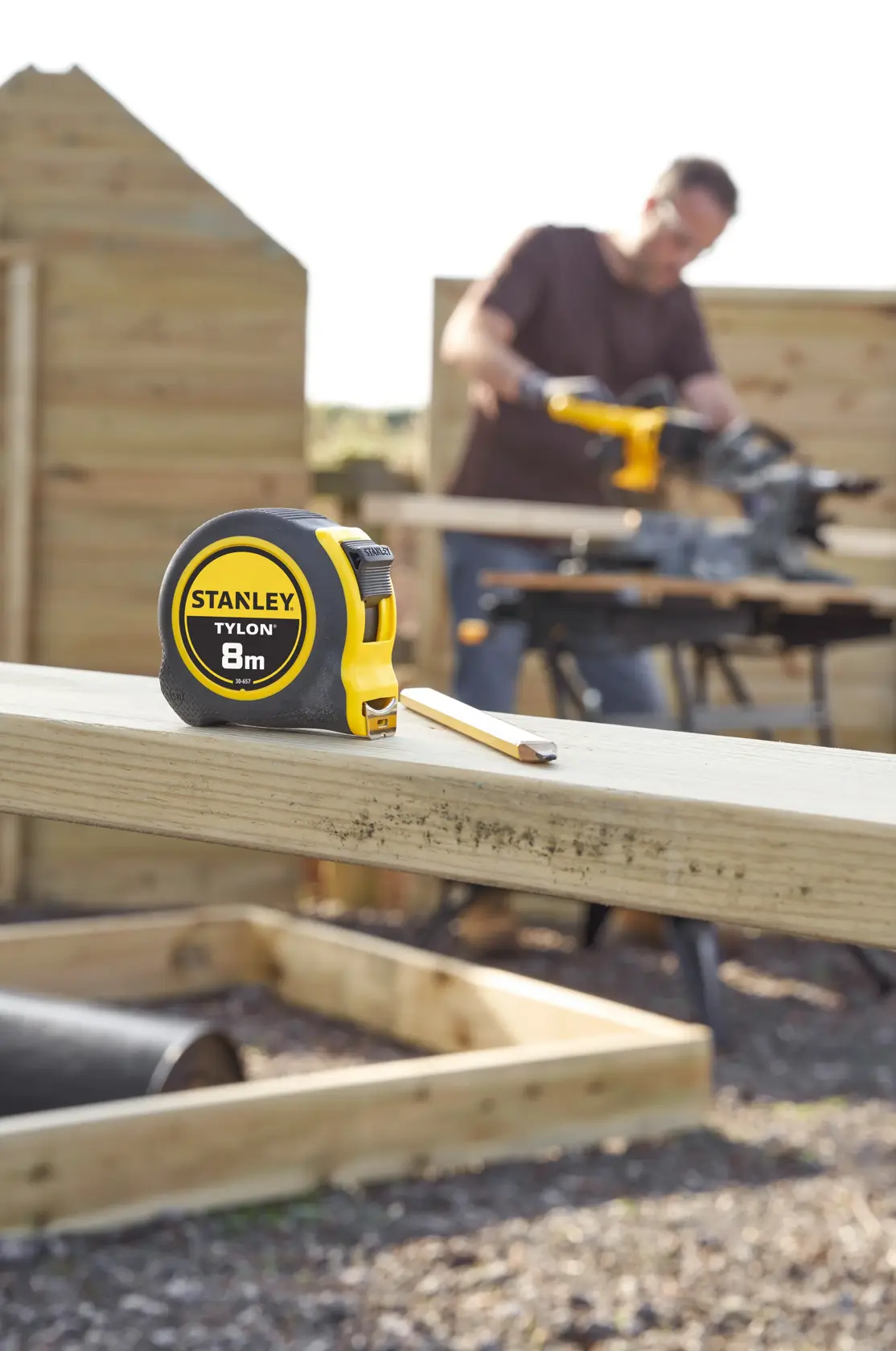 STANLEY 0-30-657 tape measure with yellow and black casing, 8m length, on timber at construction site.