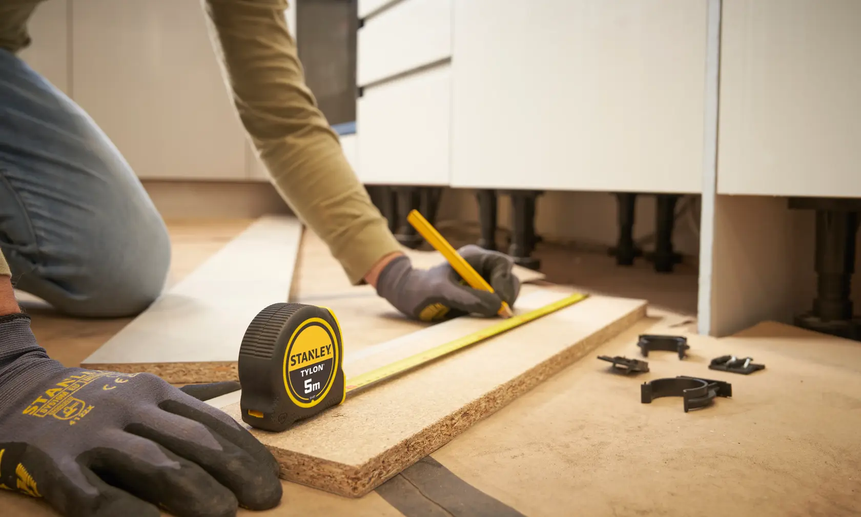 STANLEY 0-30-697 tape measure on wood plank, worker marking measurements, indoor workspace photography.