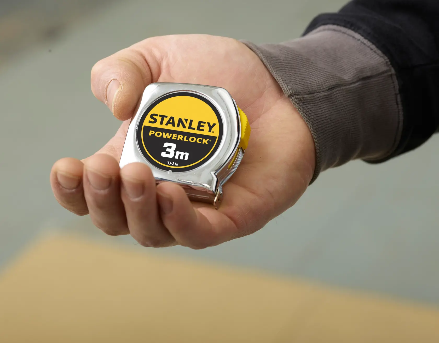 STANLEY 0-33-218 tape measure, 3m, compact chrome body, held in hand, close-up photography.