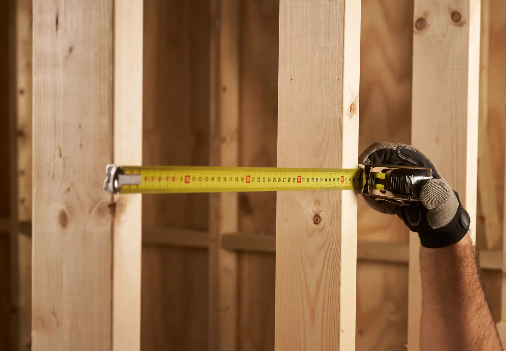 STANLEY 0-33-527 tape measure used to measure wooden studs, close-up action shot.