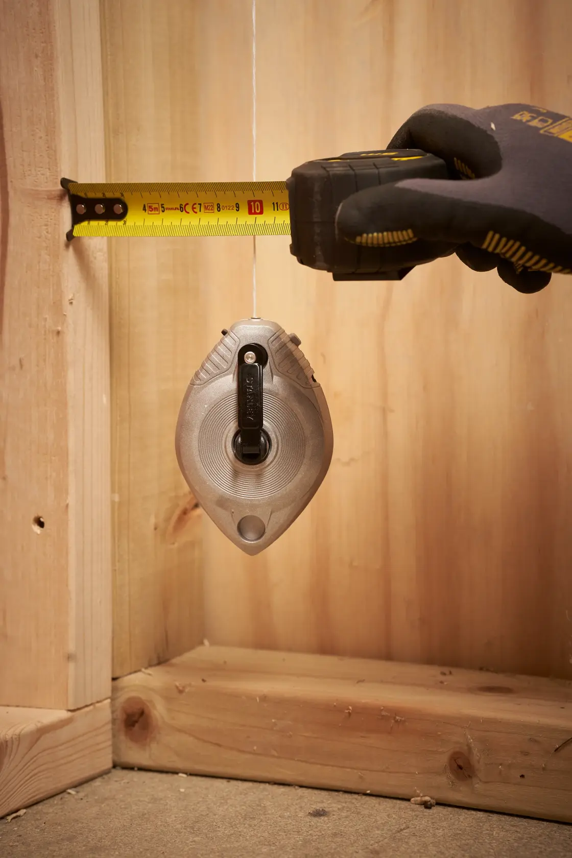 STANLEY 0-47-100 Schlagschnur-Fotografie in der Luft, umgeben von Staub und Kies, robuste Baustellenumgebung.