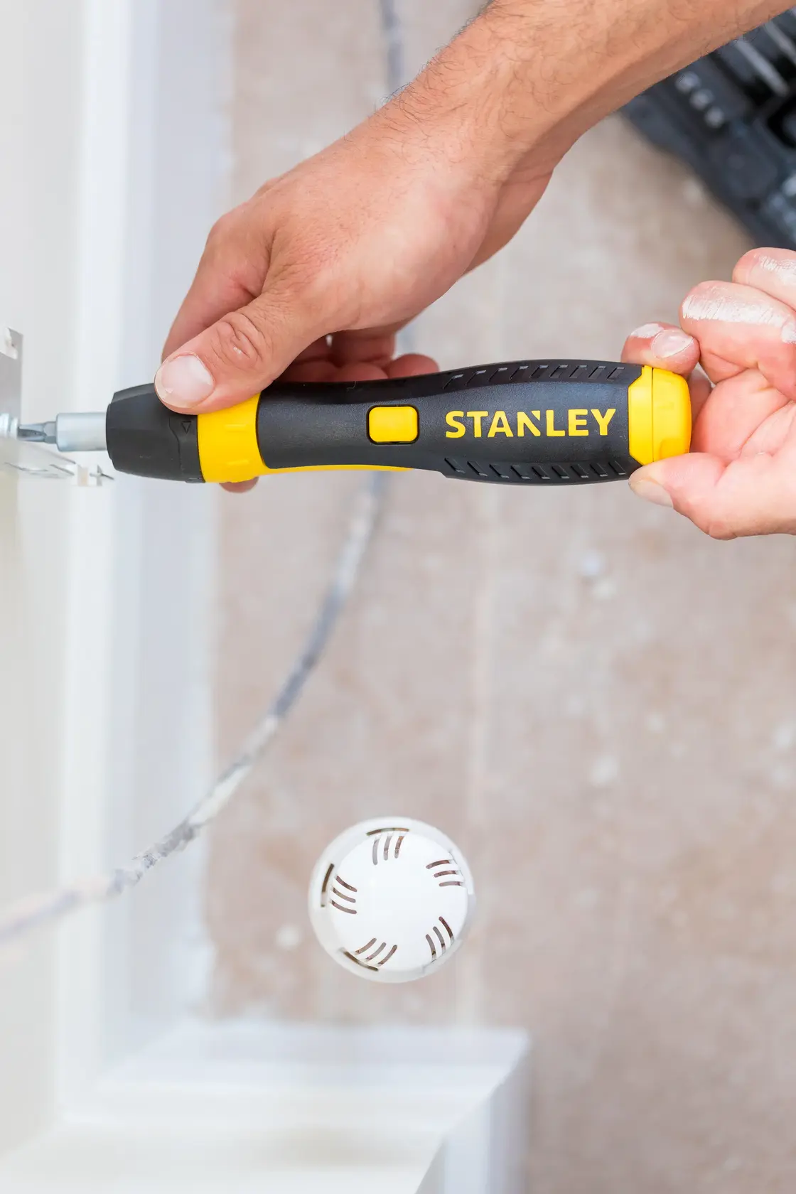STANLEY 0-63-038 ratcheting screwdriver in use, yellow and black handle, close-up during assembly.