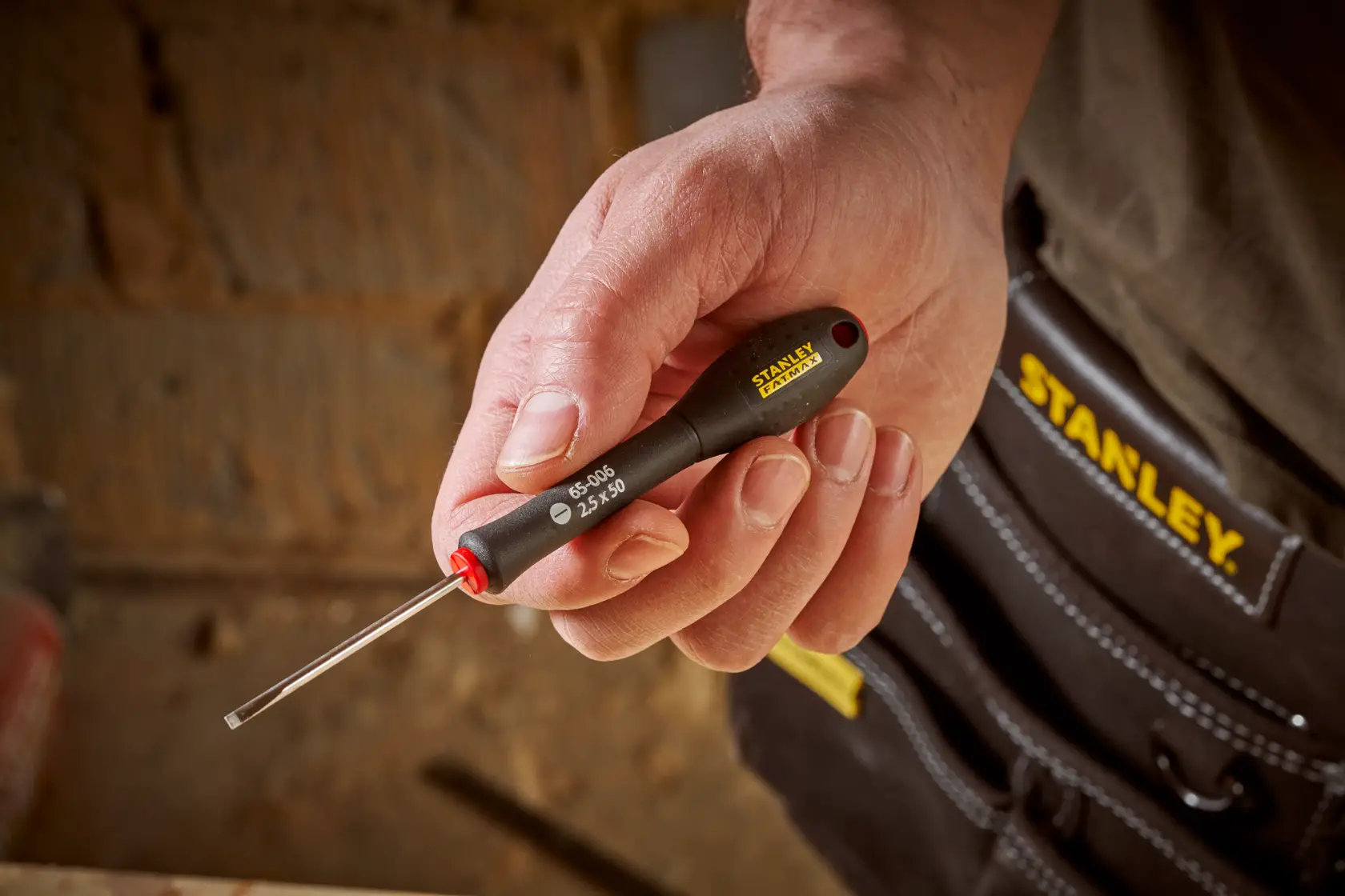 Photo of STANLEY 0-65-006 precision screwdriver with black handle and yellow logo held in hand.