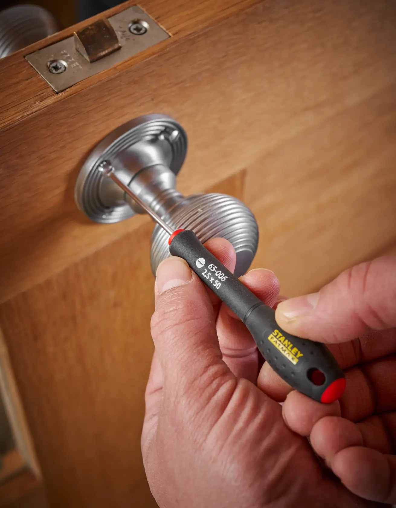 STANLEY 0-65-006 precision screwdriver in use on a metal door handle, close-up view.