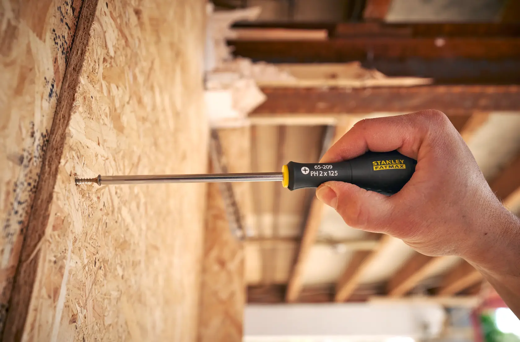 Stanley 0-65-209 screwdriver used on wood panel, close-up view of black and yellow handle.
