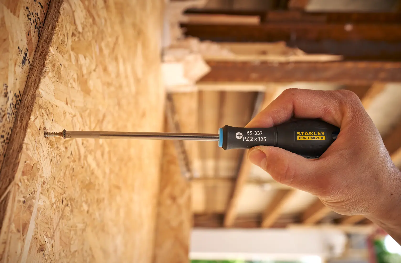 STANLEY 0-65-337 screwdriver being used to drive a screw into wooden panel, close-up hand photography.