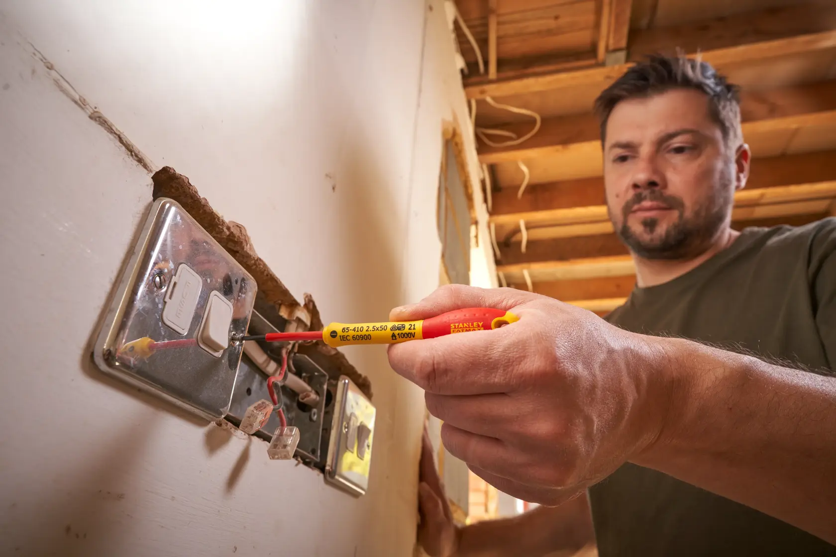 Photo of STANLEY 0-65-410 insulated screwdriver used for electrical socket wiring by a person.