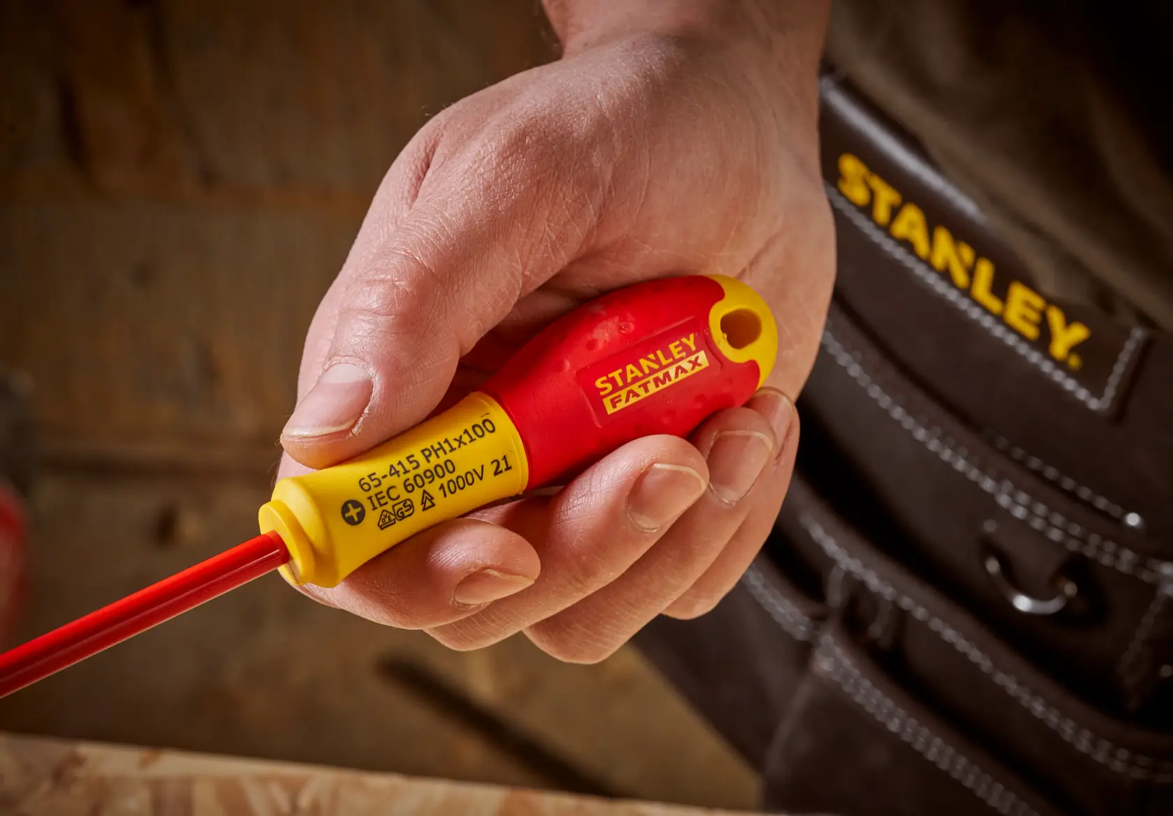 Photo of STANLEY 0-65-415 insulated screwdriver with red and yellow handle, held in hand, close-up view.