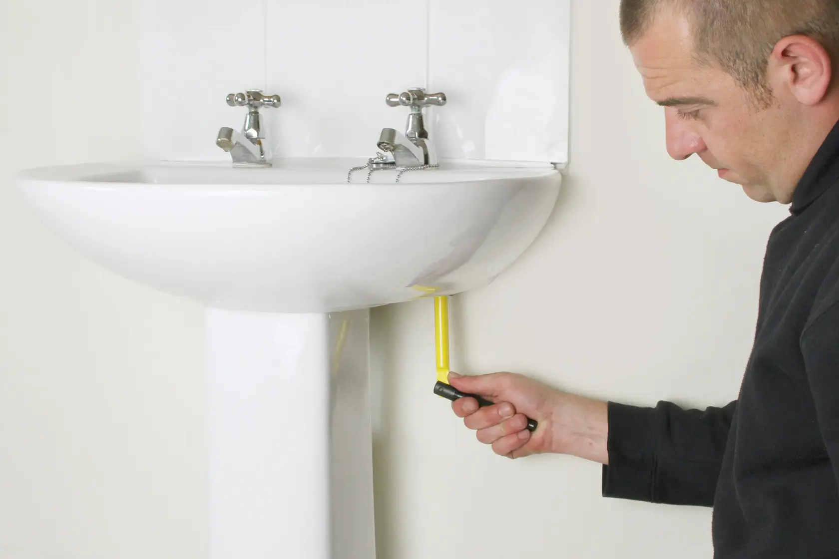 STANLEY 0-70-453 angle screwdriver in use under a white bathroom sink, side view.