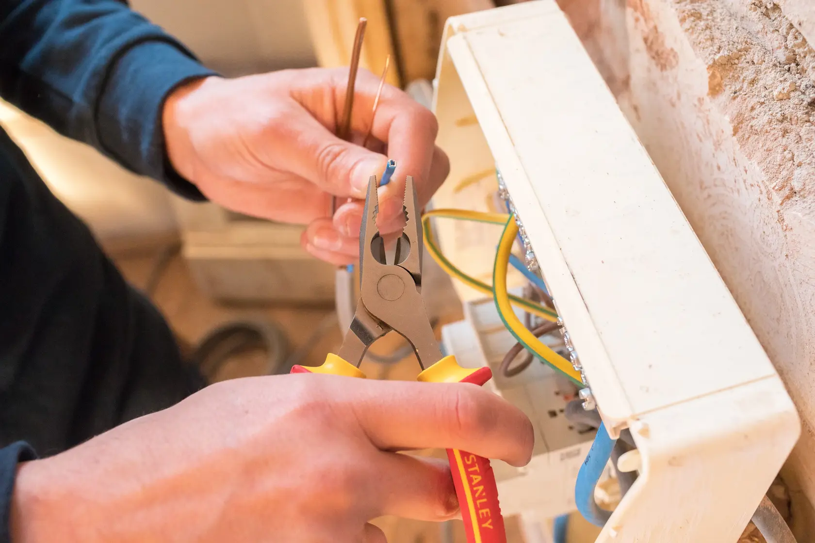 STANLEY 0-84-000 pliers in use stripping wire near electrical box, close-up angle.