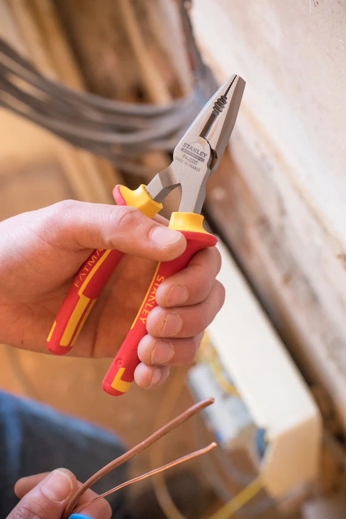 STANLEY 0-84-000 insulated pliers with red-yellow handles, photo showing tool cutting electrical wire.
