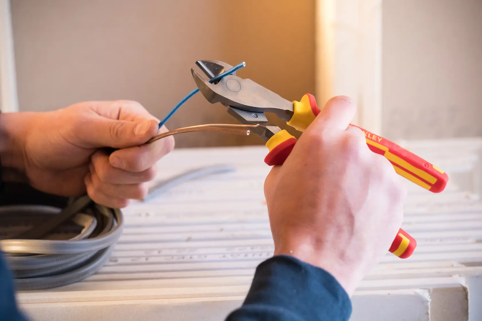 STANLEY 0-84-004 insulated pliers cutting blue wire, red and yellow handles, close-up action.