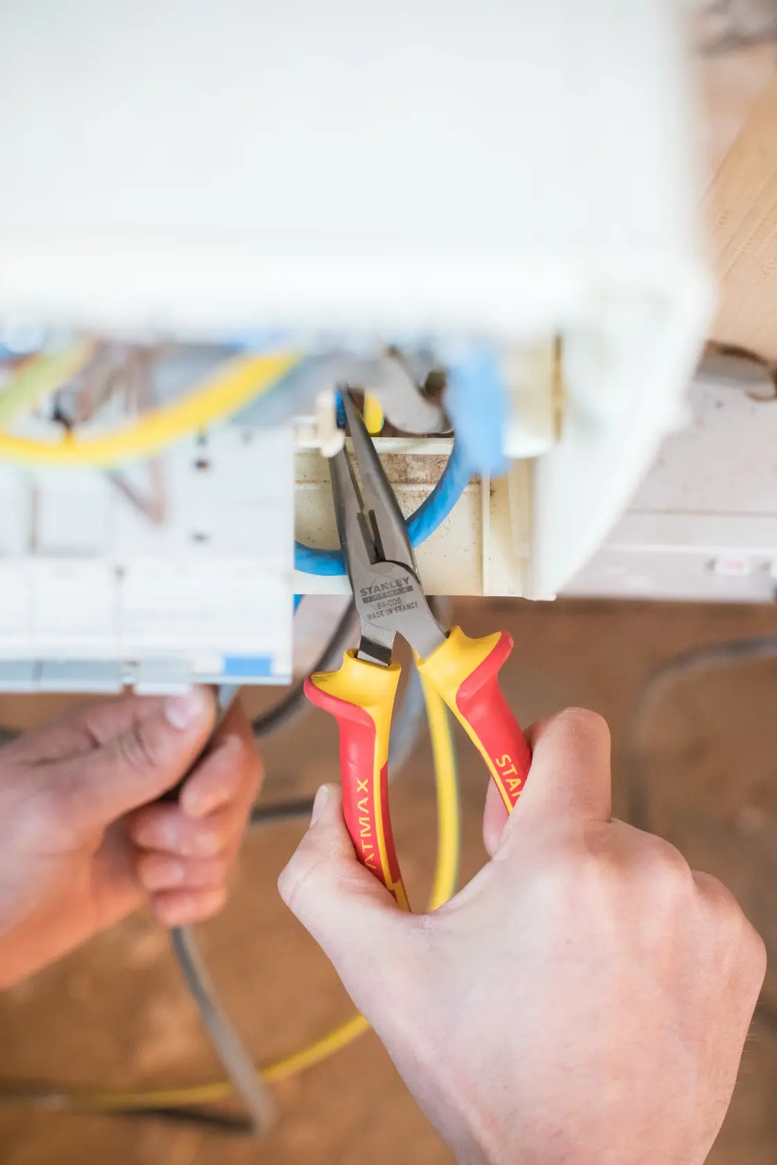STANLEY 0-84-006 long nose pliers with red-yellow handle used for electrical wiring job.