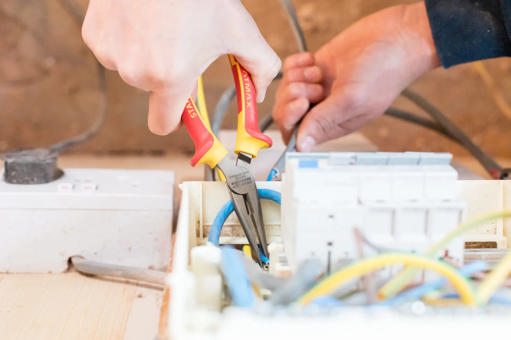 Photo of STANLEY 0-84-006 insulated pliers used for electrical wiring in a circuit box.