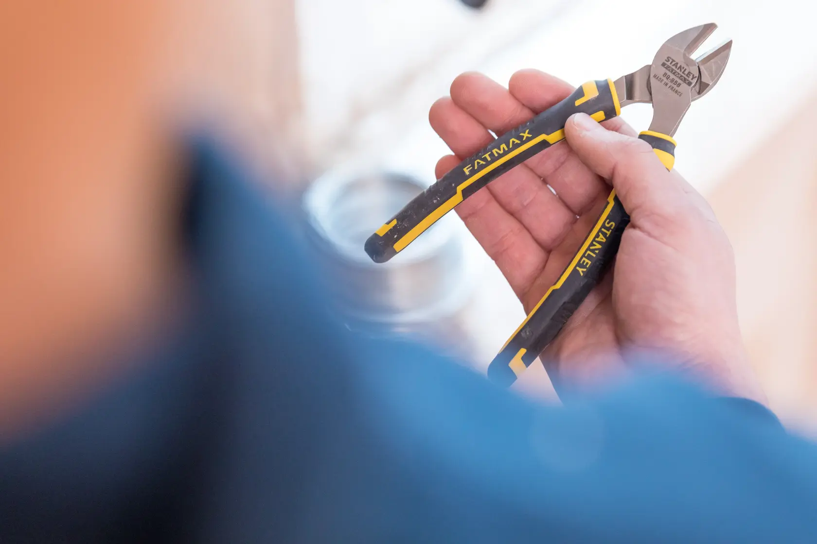 Stanley 0-89-858 diagonal cutting pliers with black and yellow handles held in hand, close-up photo.