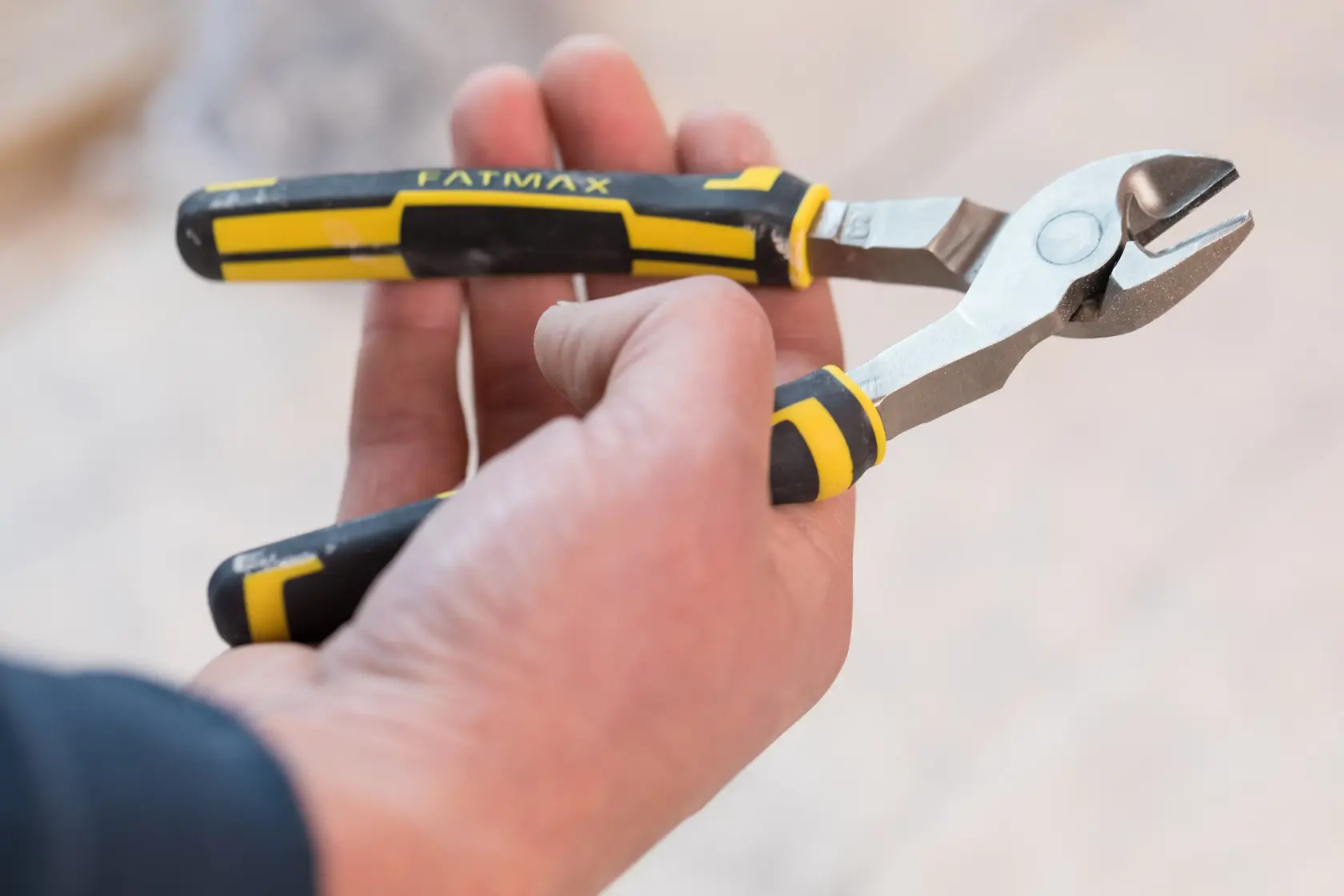 STANLEY 0-89-860 diagonal cutting pliers with black and yellow handle held in hand, side angle.
