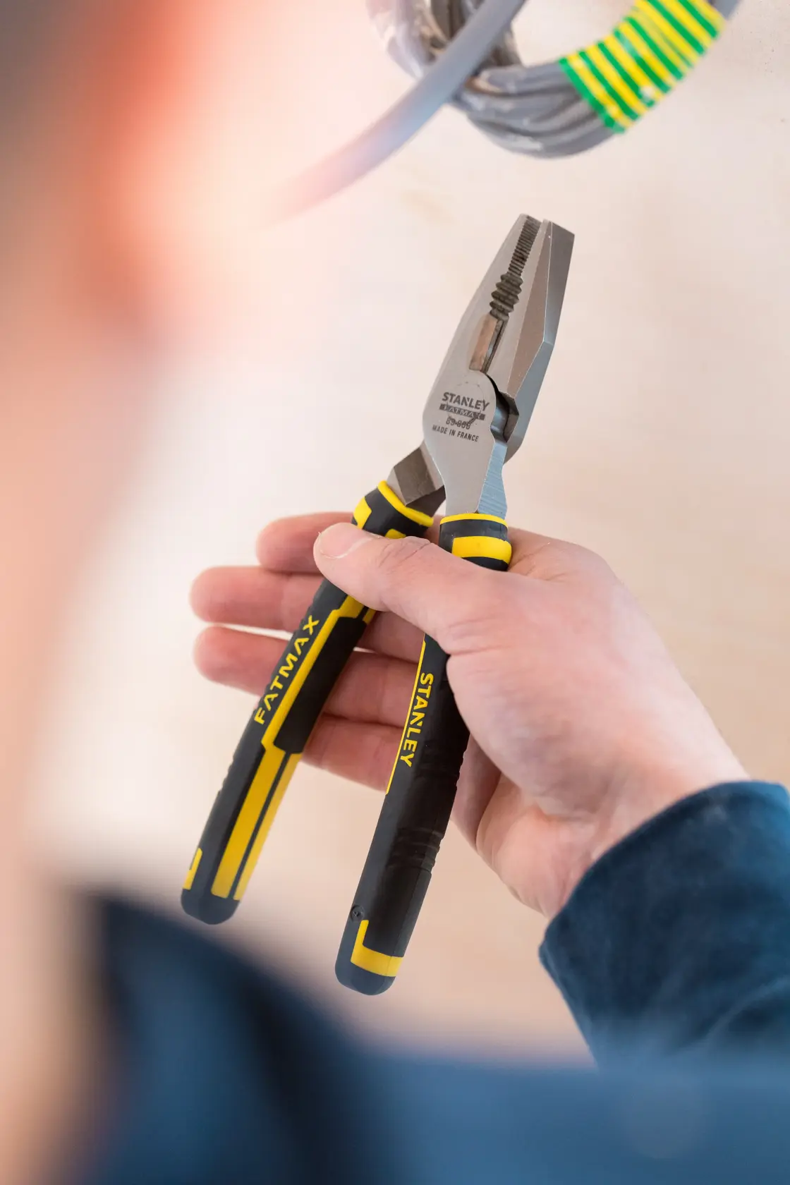 STANLEY 0-89-868 pliers with black and yellow handles held in hand, used near electrical cables.