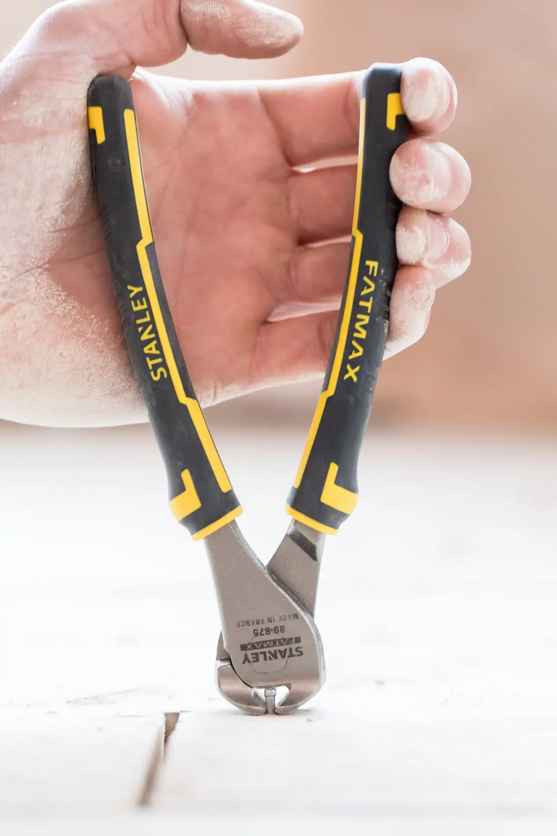 Photo of STANLEY 0-89-875 hand-held end cutting pliers with black and yellow handles, shown in use.
