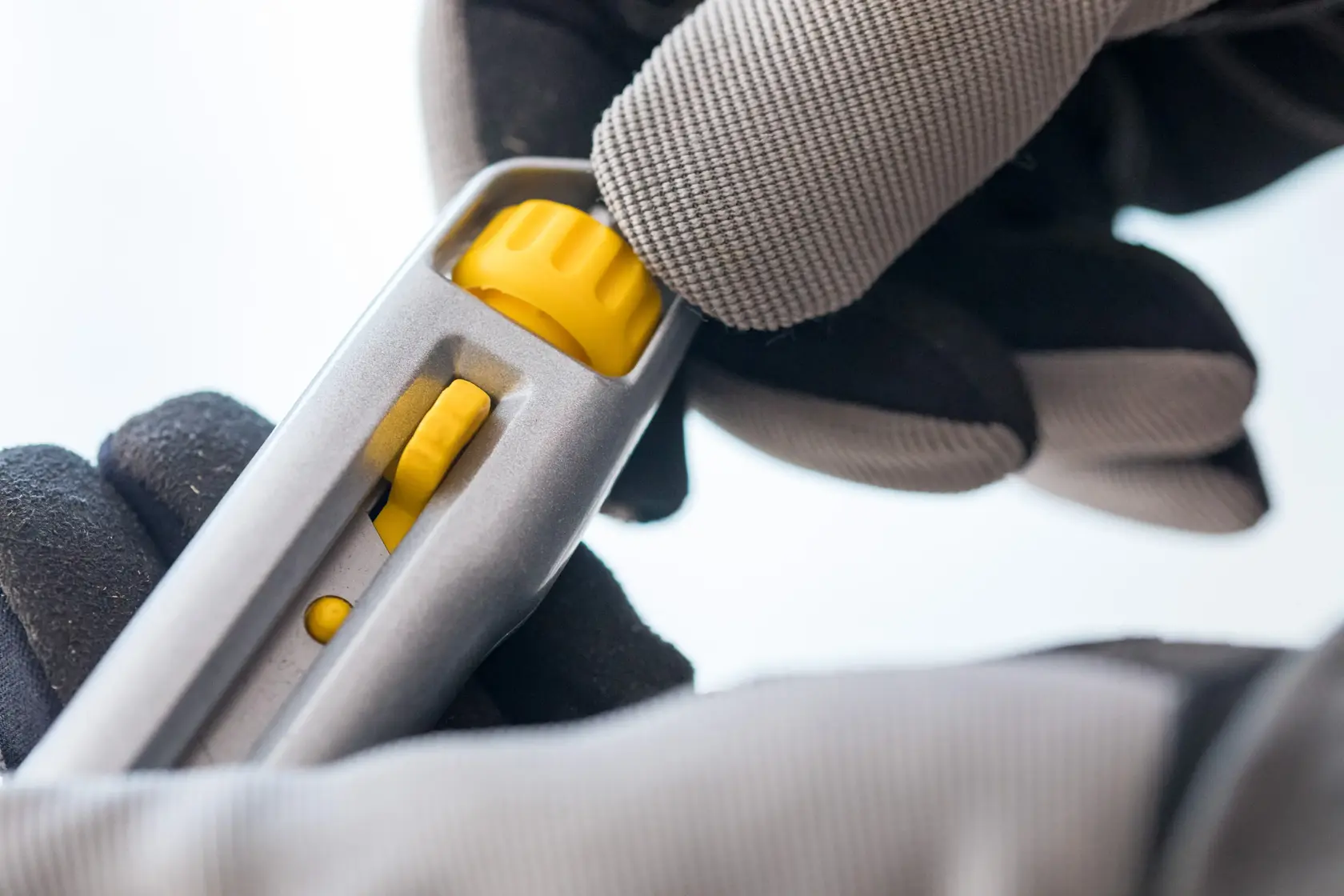 Photo of STANLEY 1-10-018 utility knife handle with yellow adjustment wheel in gloved hand.