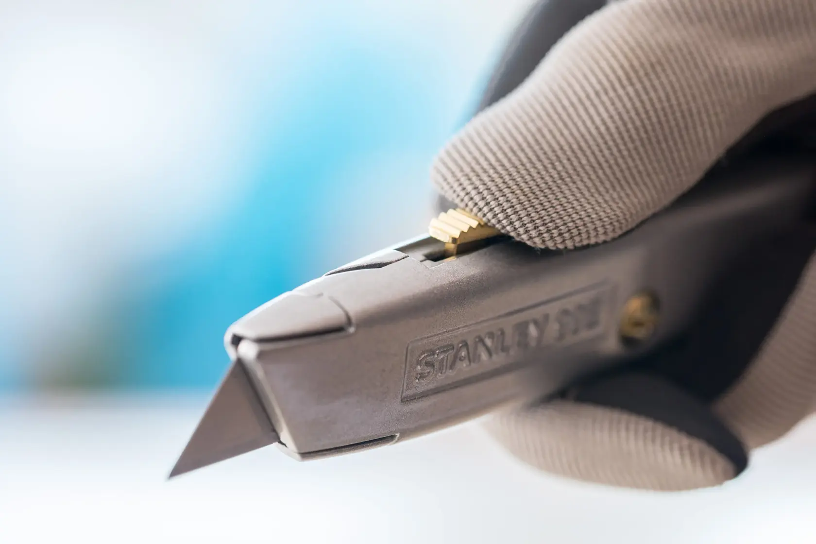 Photo of STANLEY 1-10-099 utility knife held in gloved hand, showing blade and textured handle.
