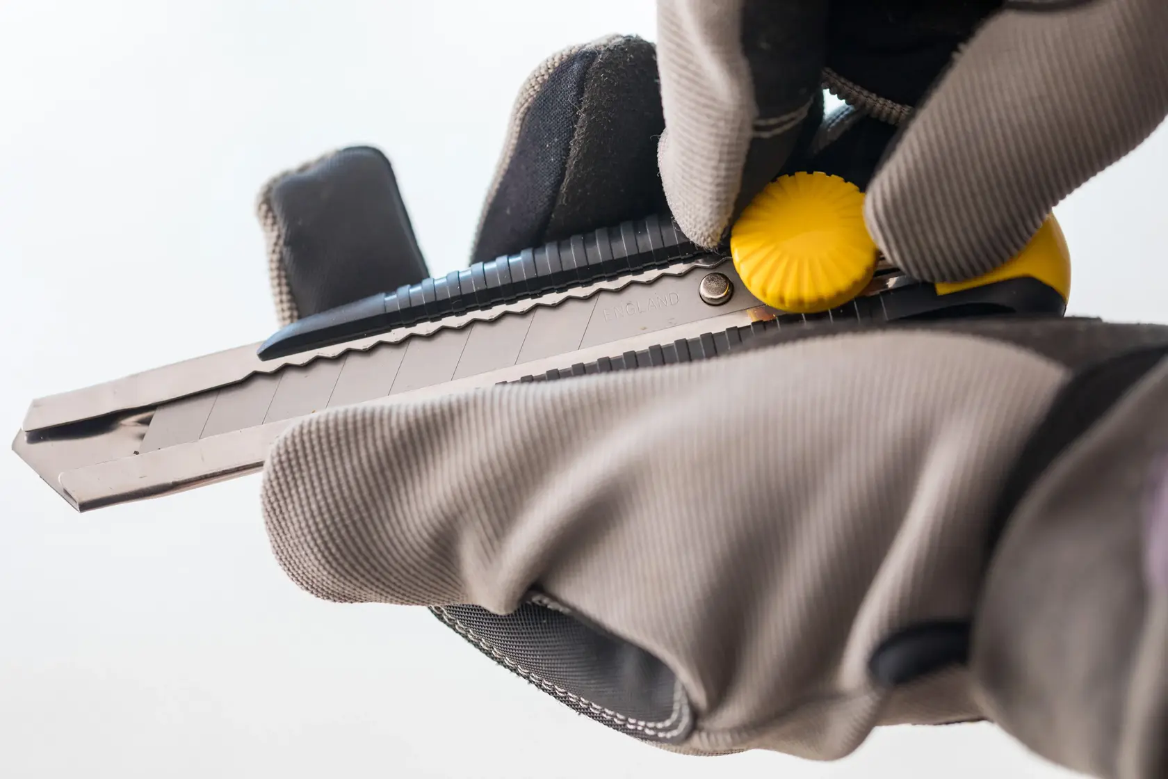 STANLEY 1-10-418 utility knife with yellow wheel held by gloved hands, close-up view.