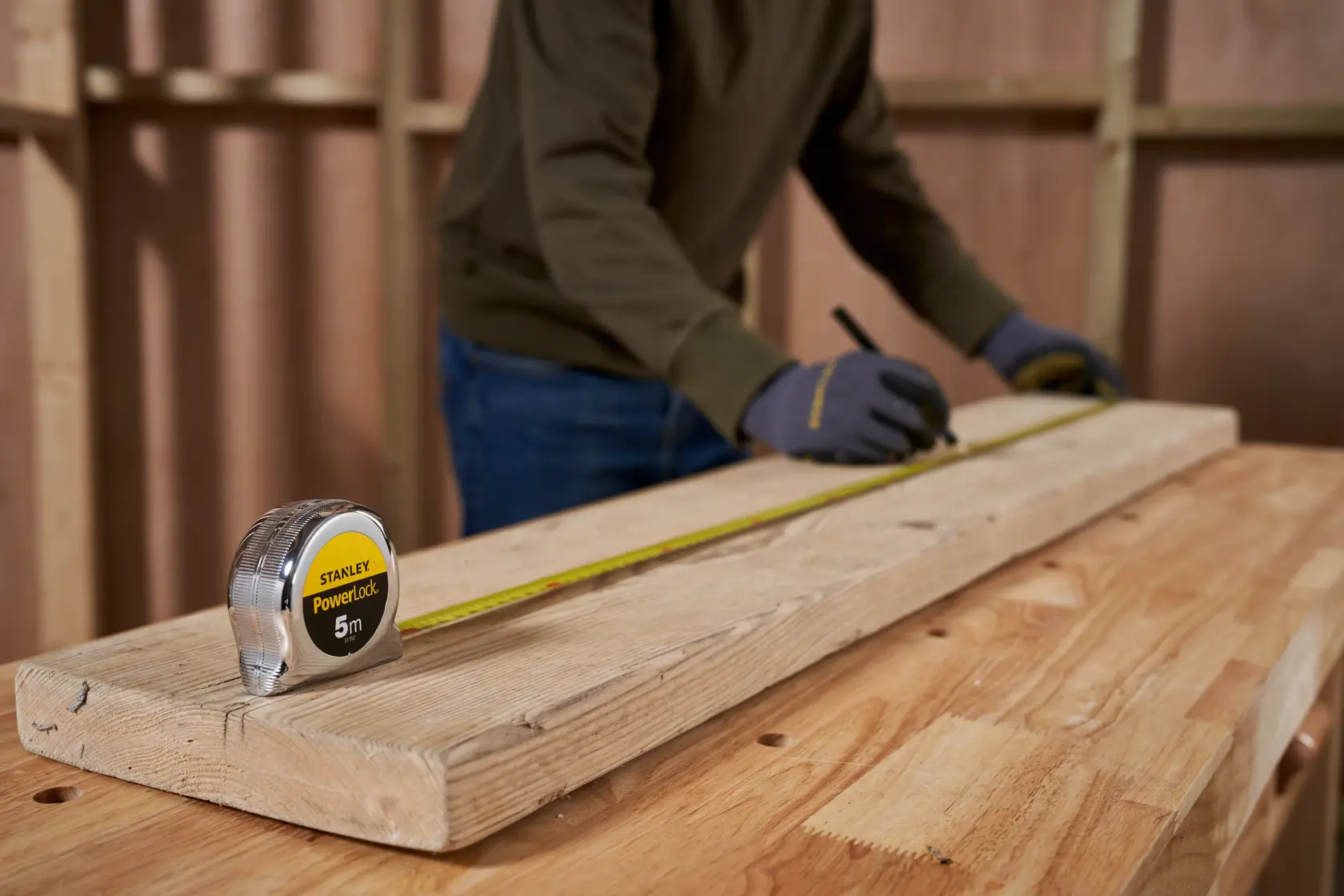 STANLEY 1-33-522 tape measure on wood plank, person measuring for carpentry.