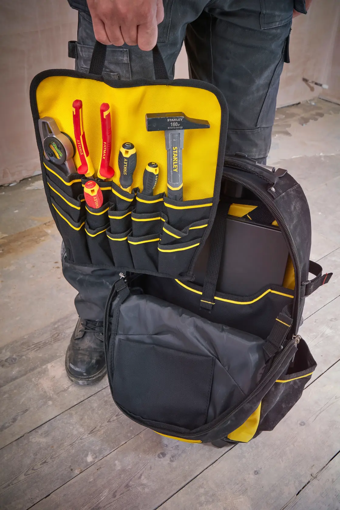 STANLEY 1-79-215 tool backpack open, showing yellow and black pockets with assorted hand tools, front view.