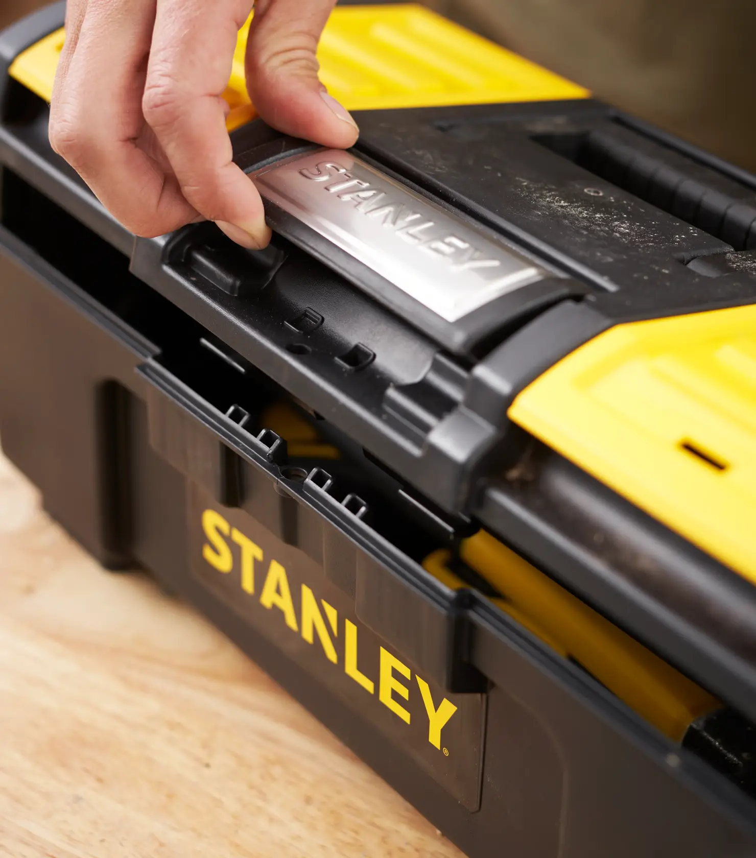 Photo of STANLEY 1-79-216 tool box being opened, black and yellow plastic, close-up angle.