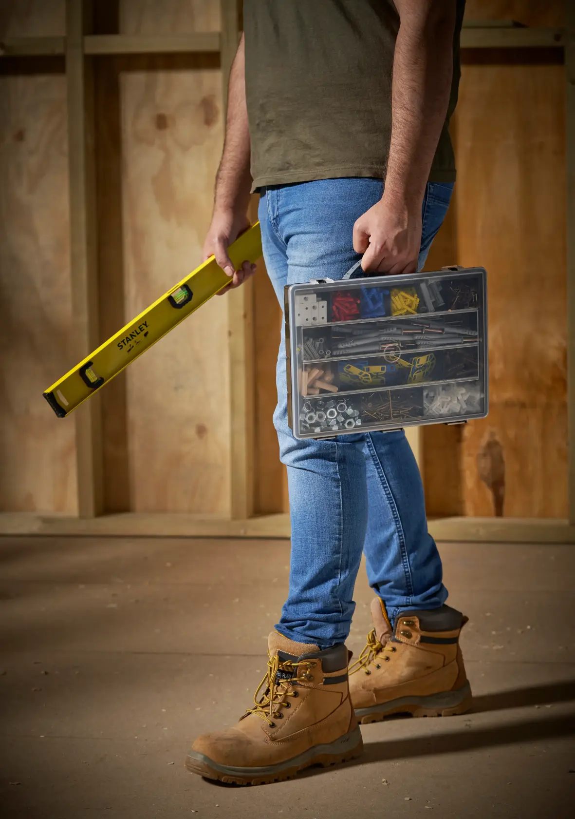 STANLEY 1-92-761 hardware organizer case held by person wearing tan work boots in construction setting.