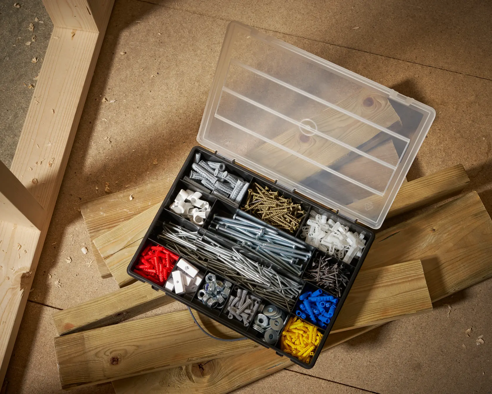STANLEY 1-92-761 organizer box top view with assorted screws, anchors, nuts and bolts on workshop floor.