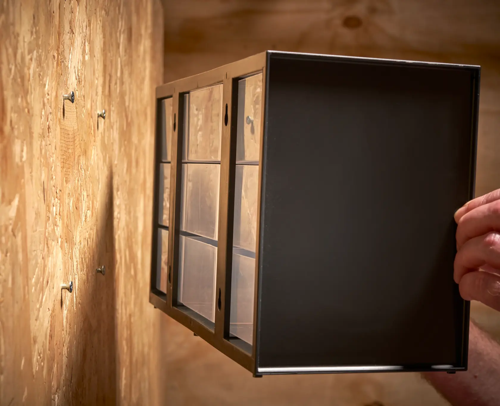 STANLEY 1-93-978 organizer cabinet being mounted on wall, shown from side angle, wood background.