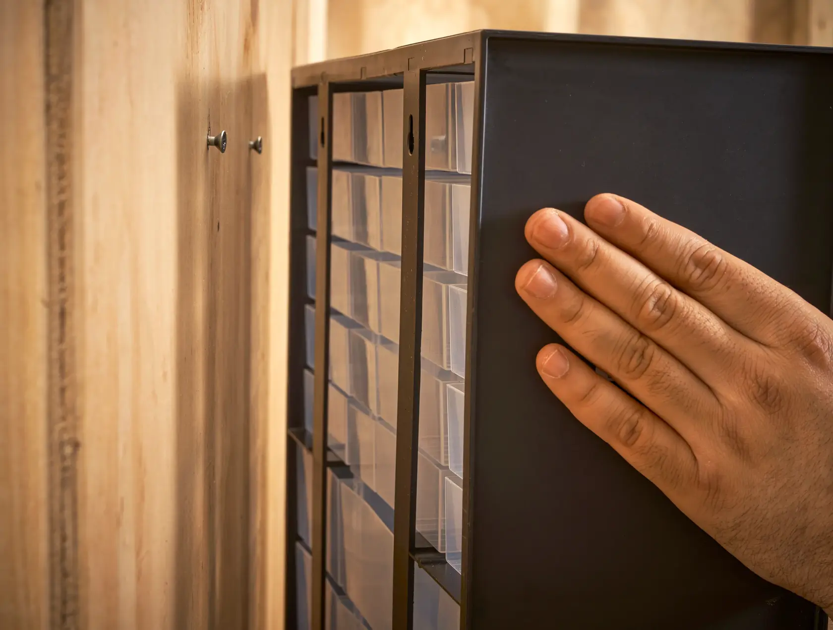 STANLEY 1-93-981 storage cabinet being mounted on wall by hand, close-up side angle.