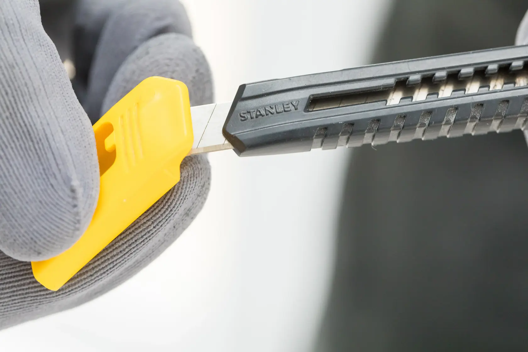 Photo of STANLEY 2-10-150 utility knife with black handle and yellow blade snapper, close-up in use.