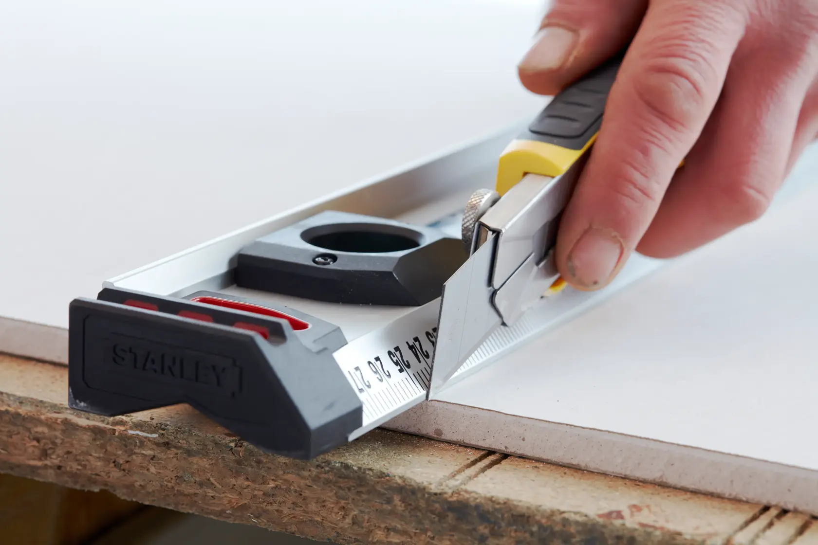 Photo of STANLEY 2-11-725 utility knife cutting along a metal ruler on a board surface.