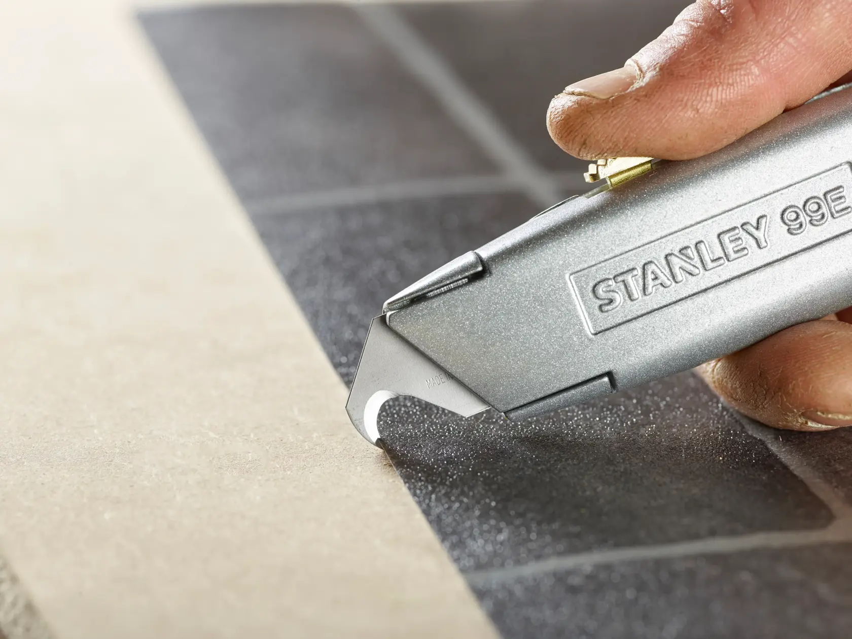 STANLEY 2-11-983 utility knife cutting tile, close-up photography.