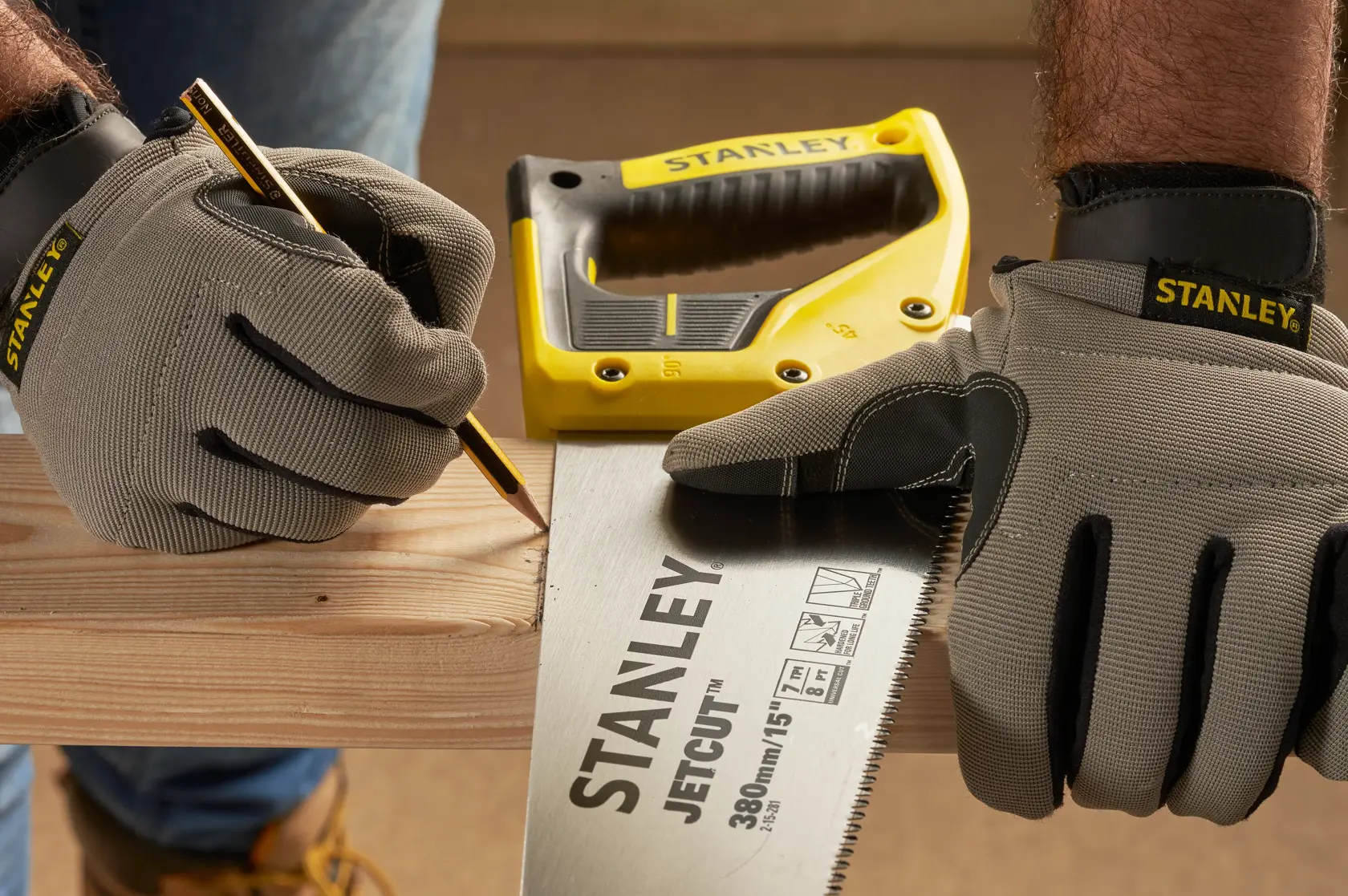 Photo of STANLEY 2-15-281 hand saw on wood, worker with STANLEY gloves marking cut line, photography category.