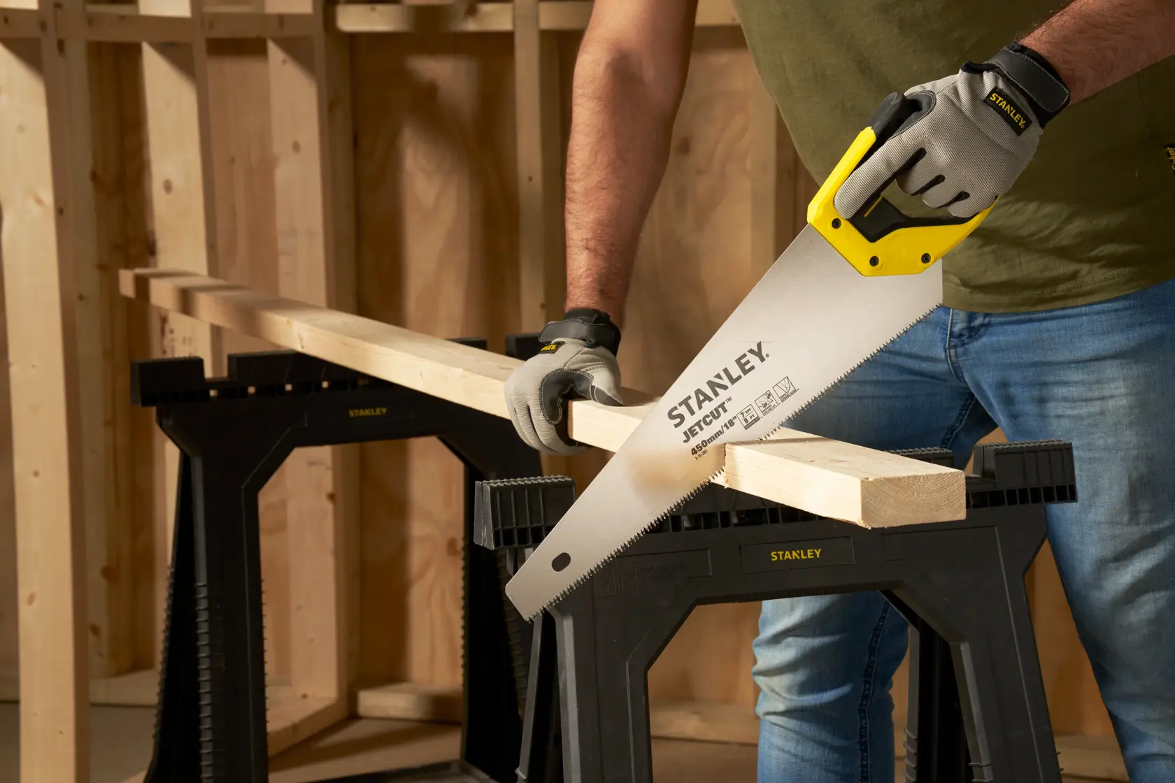 STANLEY 2-15-283 hand saw cutting wood on black sawhorse in workshop, close-up angle.