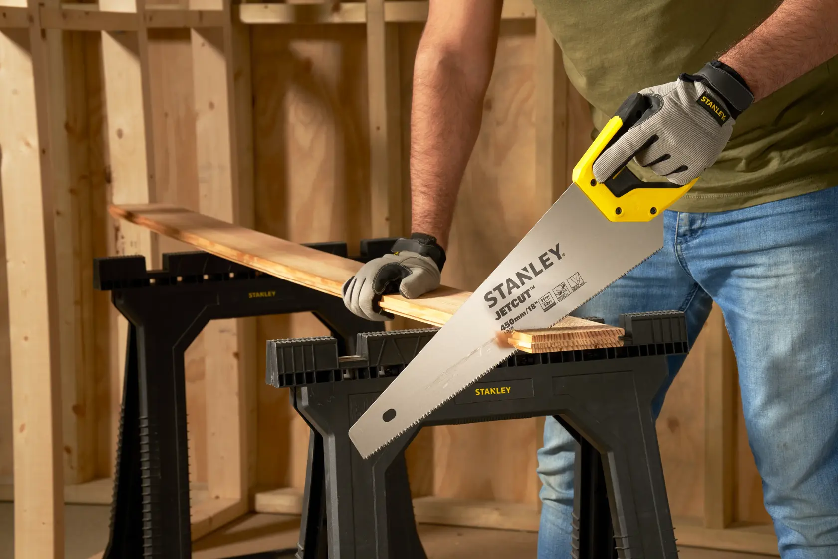 Photo of STANLEY 2-15-595 hand saw cutting wood, person wearing gloves in a workshop setting.