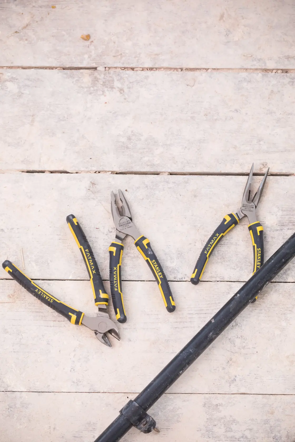 STANLEY 4-84-488 plier set with black and yellow handles, flat lay on wooden surface.