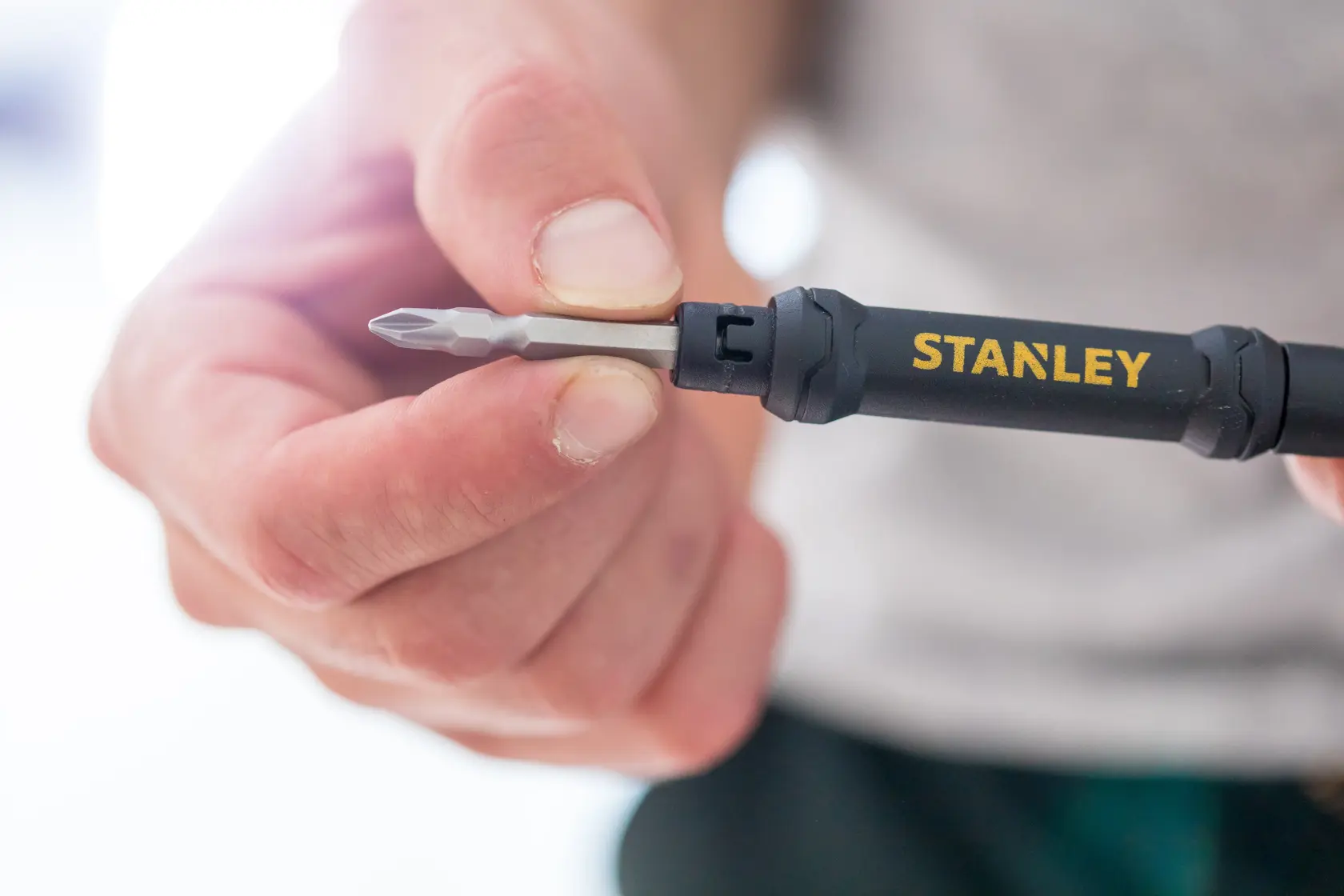 Photo of STANLEY 66-344M screwdriver with black handle and yellow logo held in hand, close-up view.