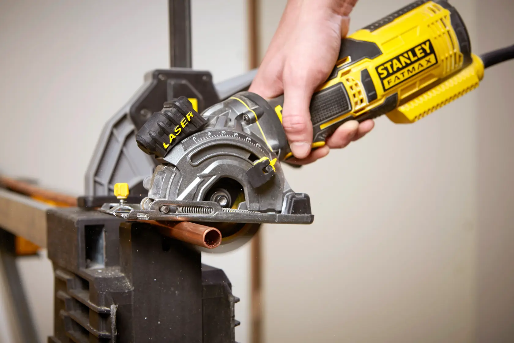 Photo of STANLEY FME380K circular saw cutting copper pipe, close-up of tool in use.