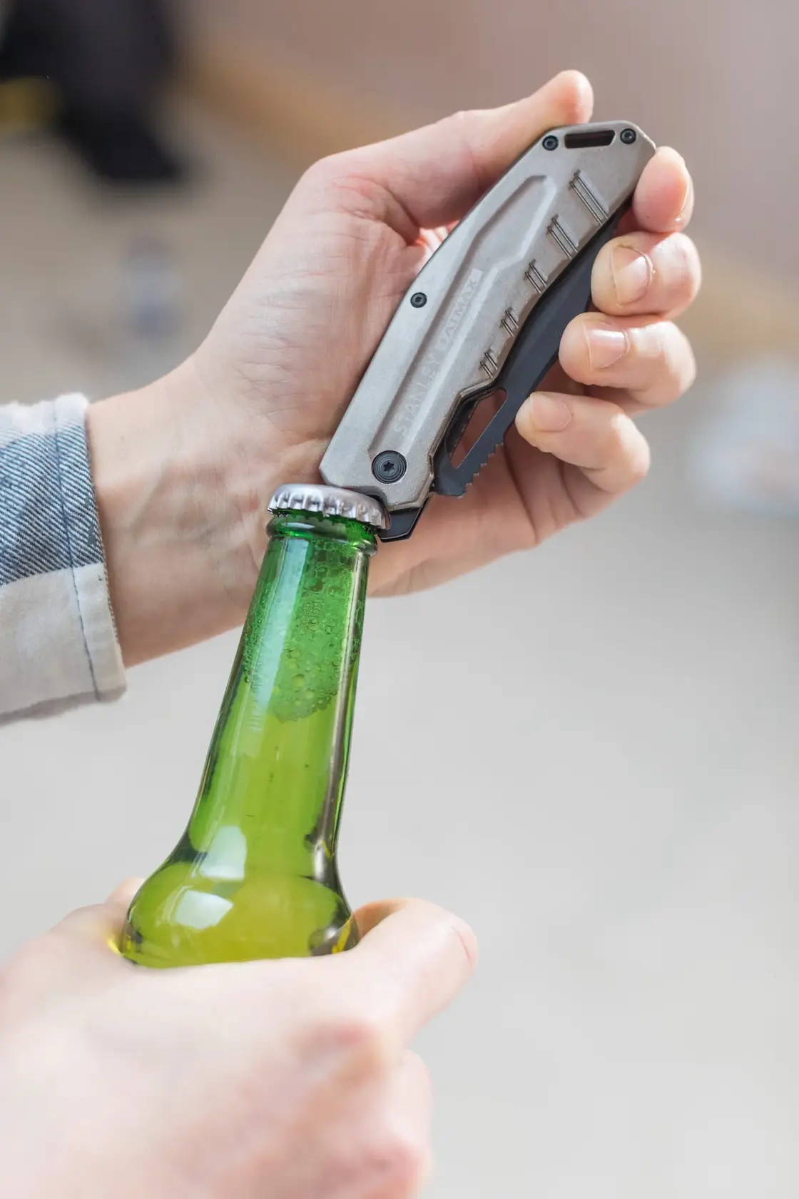 Photo of STANLEY FMHT0-10312 folding utility knife used to open a green glass bottle.
