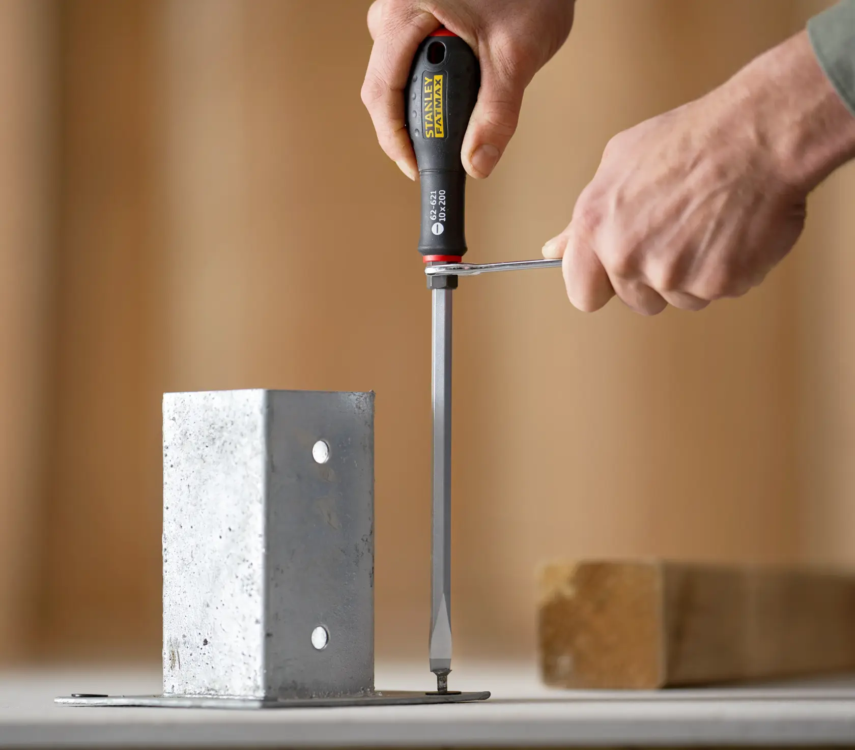 STANLEY FMHT0-62621 screwdriver used on a metal bracket, close-up with hands holding tool.