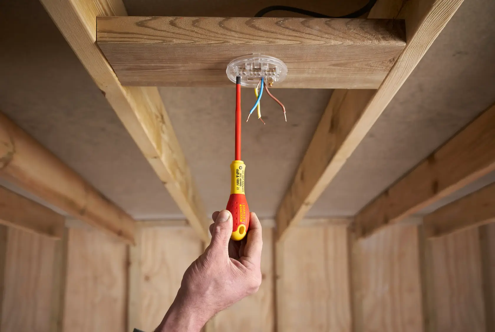 STANLEY FMHT0-62649 insulated screwdriver used on ceiling electrical junction, indoor wood frame.