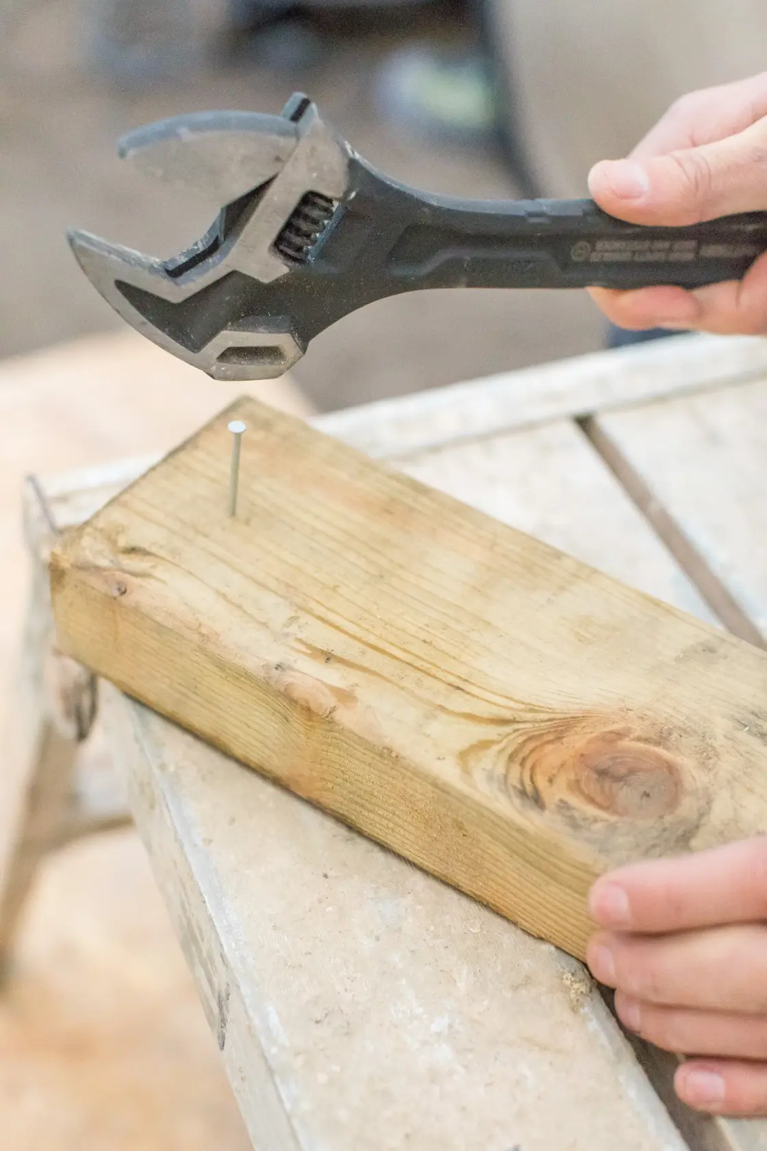 STANLEY FMHT0-75081 adjustable wrench used on nail in wooden plank, close angle.