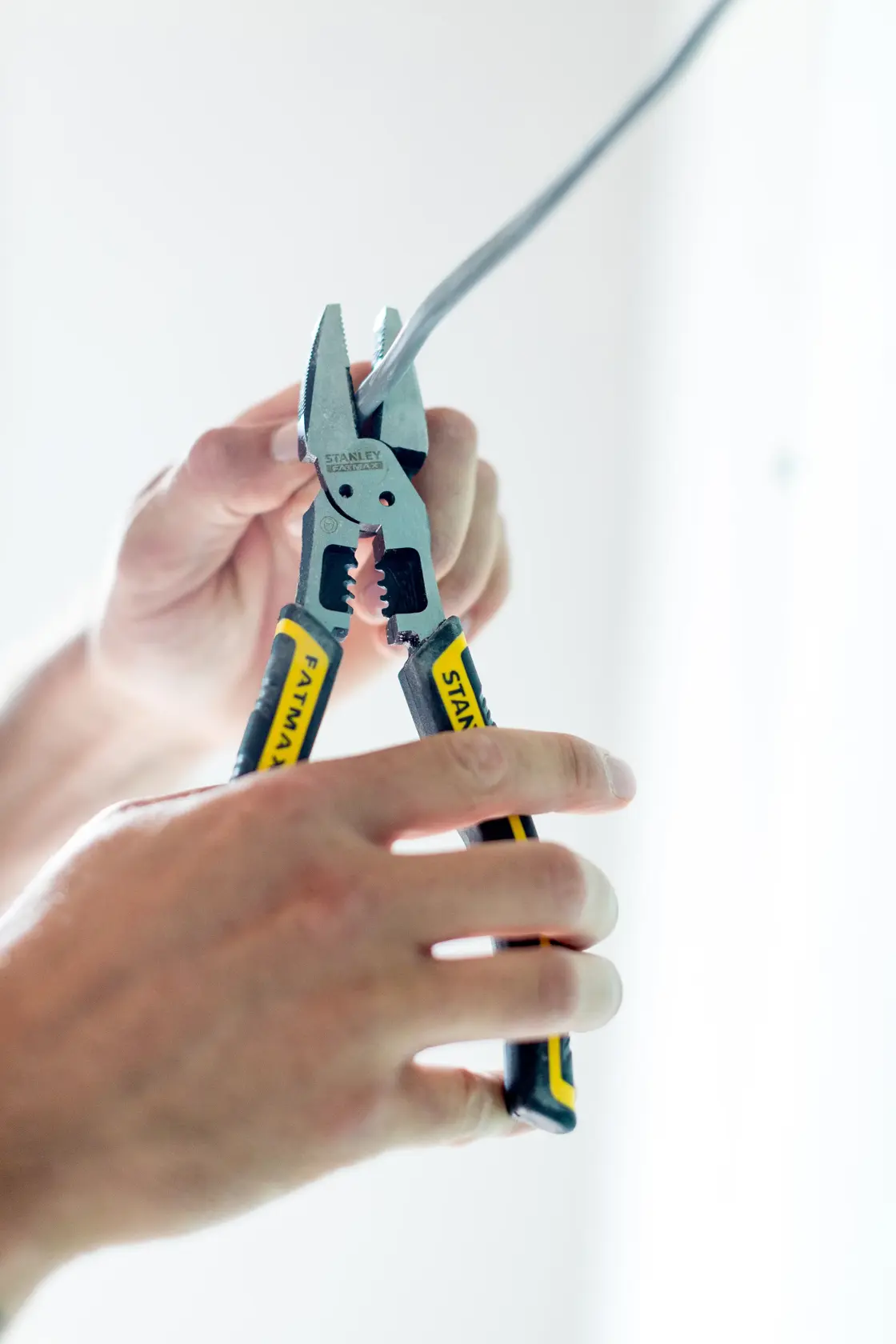 Stanley FMHT0-75469 pliers cutting wire, close-up of tool in use, yellow and black ergonomic handles.