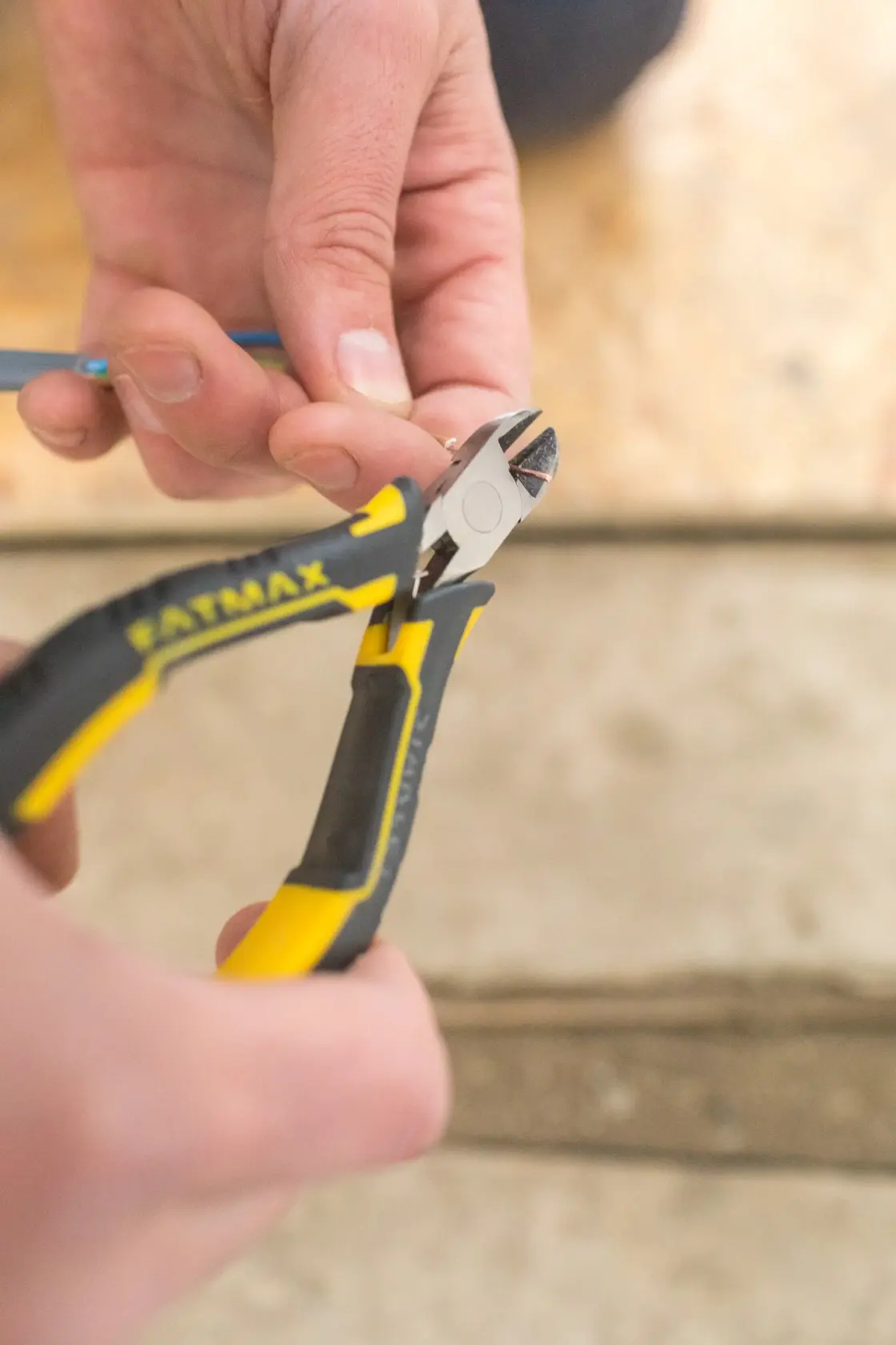 Photo of STANLEY FMHT0-80518 diagonal pliers cutting a wire, close-up view.
