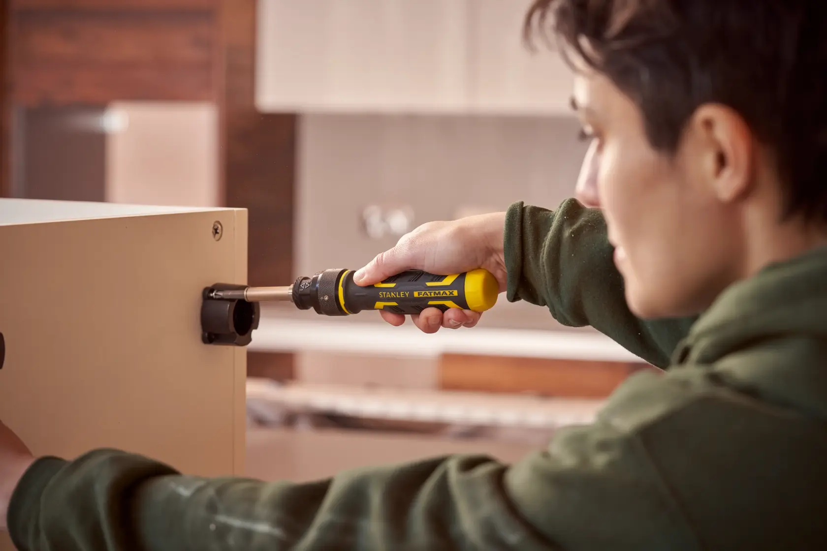 Stanley FMHT62692-0 screwdriver in use to assemble furniture, yellow and black handle, indoor setting.
